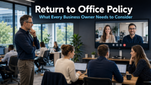 Business owner and team members in a modern bright office setting with some staff working at desks and a video call screen showing remote colleagues, representing the return to office policy debate facing businesses today